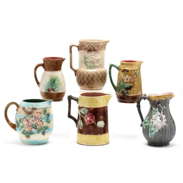 a-group-of-six-majolica-pitchers