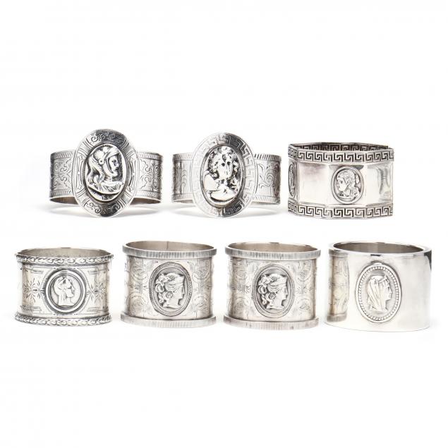 an-assembled-set-of-seven-silver-medallion-napkin-rings